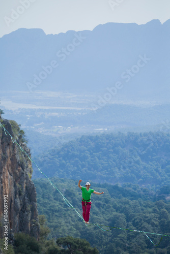 A tightrope walker walks along a cable stretched over a canyon.