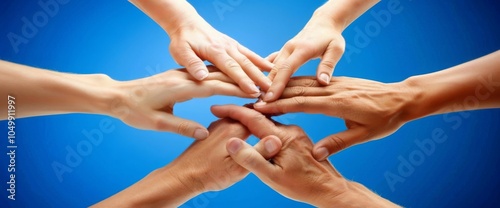 Close-up of hands put together in a gesture of team support and unity on a blue background. Conceptual image representing community, collaboration, teamwork, partnership.