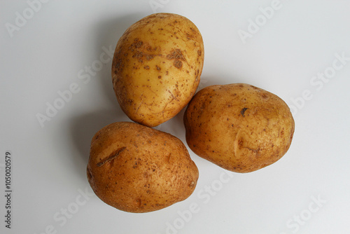 Three potatoes unpeeled, isolated on white background