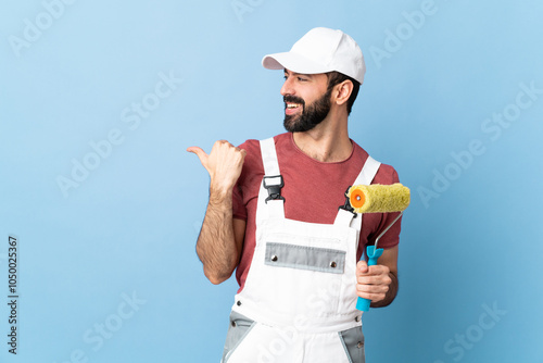 Fototapeta Naklejka Na Ścianę i Meble -  Adult painter man over isolated blue background pointing to the side to present a product