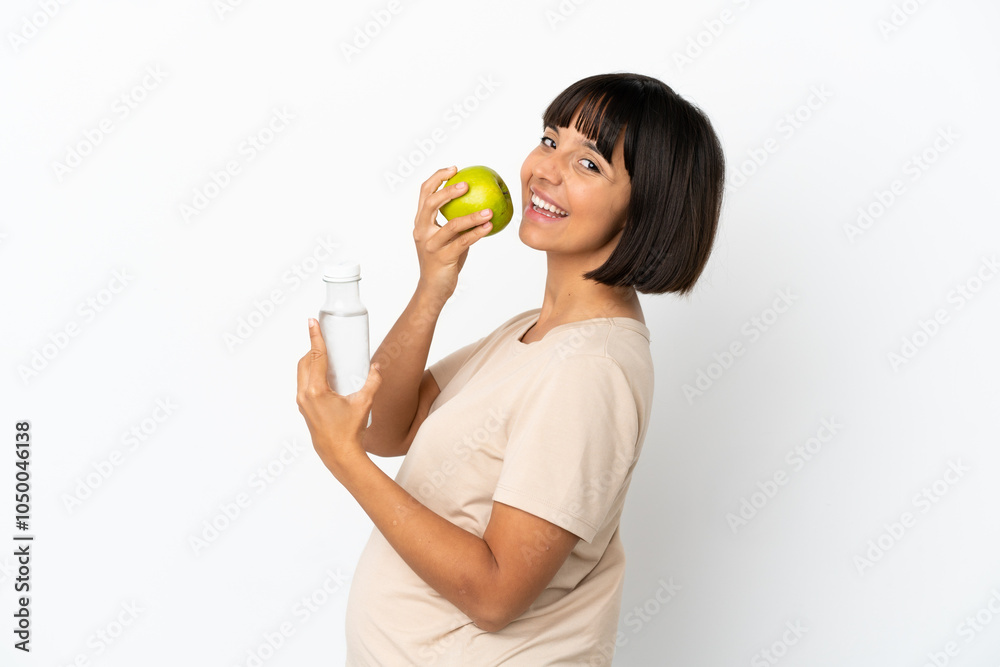 Young mixed race pregnant woman isolated on white background with an apple and with a bottle of water Young mixed race pregnant woman isolated on white background with an apple and with a bottle of water