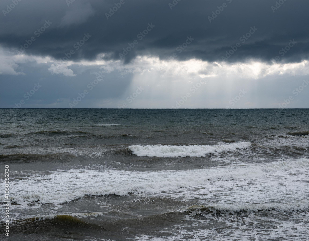 Dark clouds gather over a choppy ocean as the sun breaks through in the distance on a moody afternoon Dark clouds gather over a choppy ocean as the sun breaks through in the distance on a moody afternoon