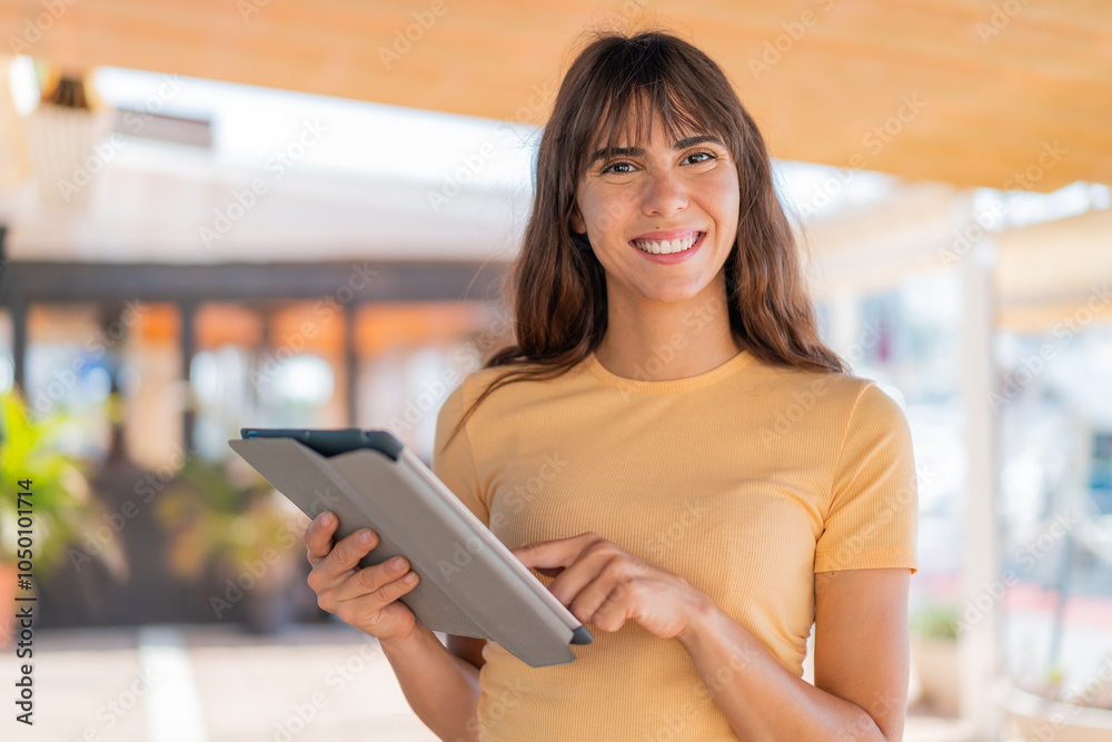 Young woman at outdoors touching the tablet screen with happy expression Young woman at outdoors touching the tablet screen with happy expression