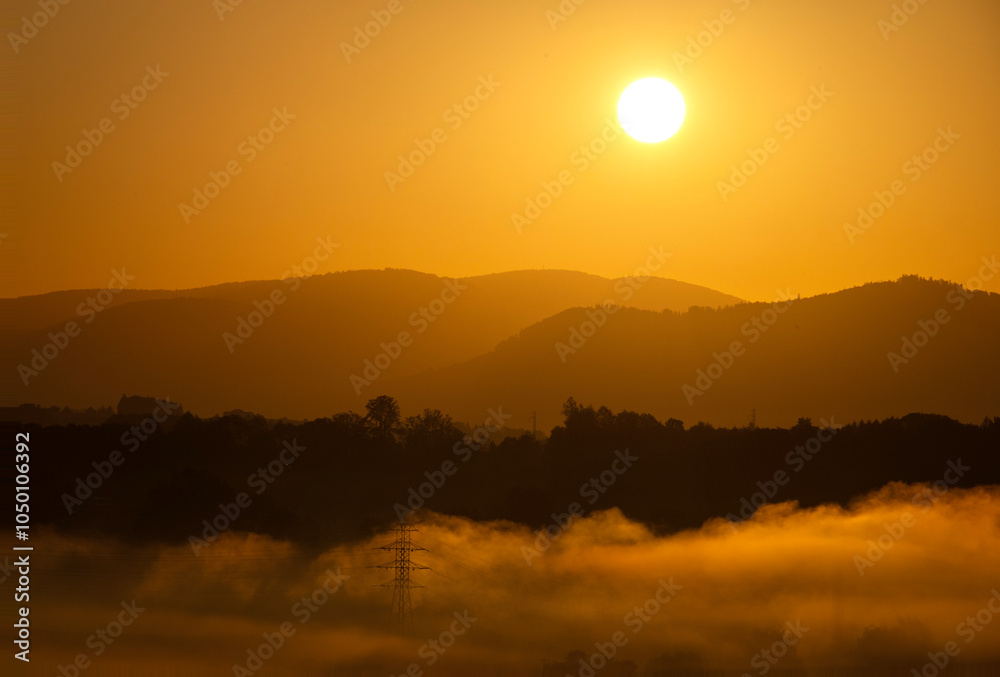 Sunrise over misty hills with mountains in the background Sunrise over misty hills with mountains in the background