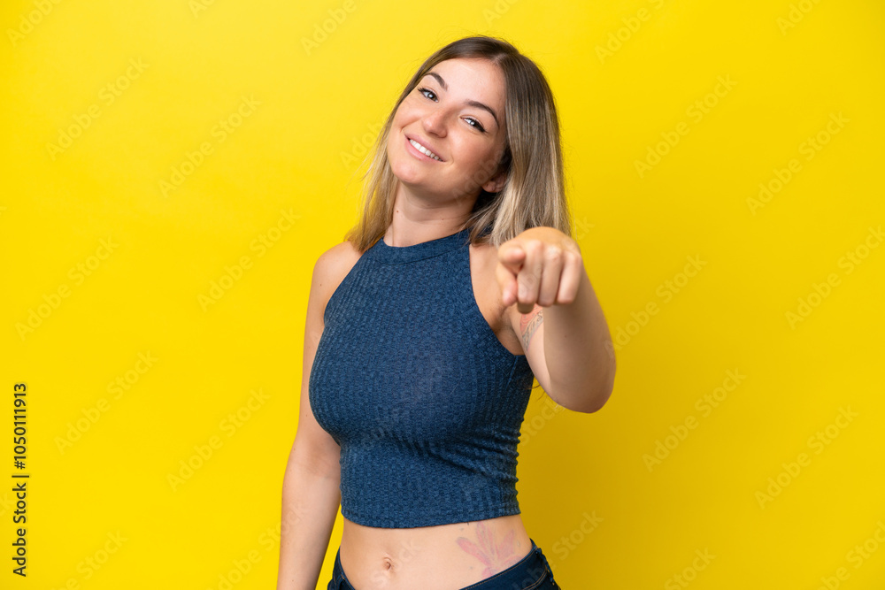 Young Rumanian woman isolated on yellow background pointing front with happy expression Young Rumanian woman isolated on yellow background pointing front with happy expression