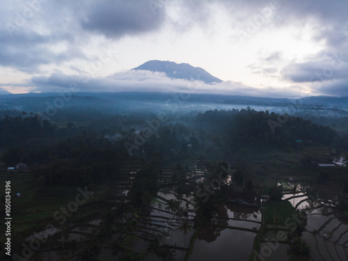 A serene view of rice terraces shrouded in mist with a towering mountain in the background. photo