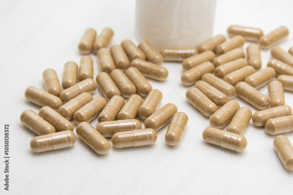 Herbal pills spilling out of bottle on white background Herbal pills spilling out of bottle on white background
