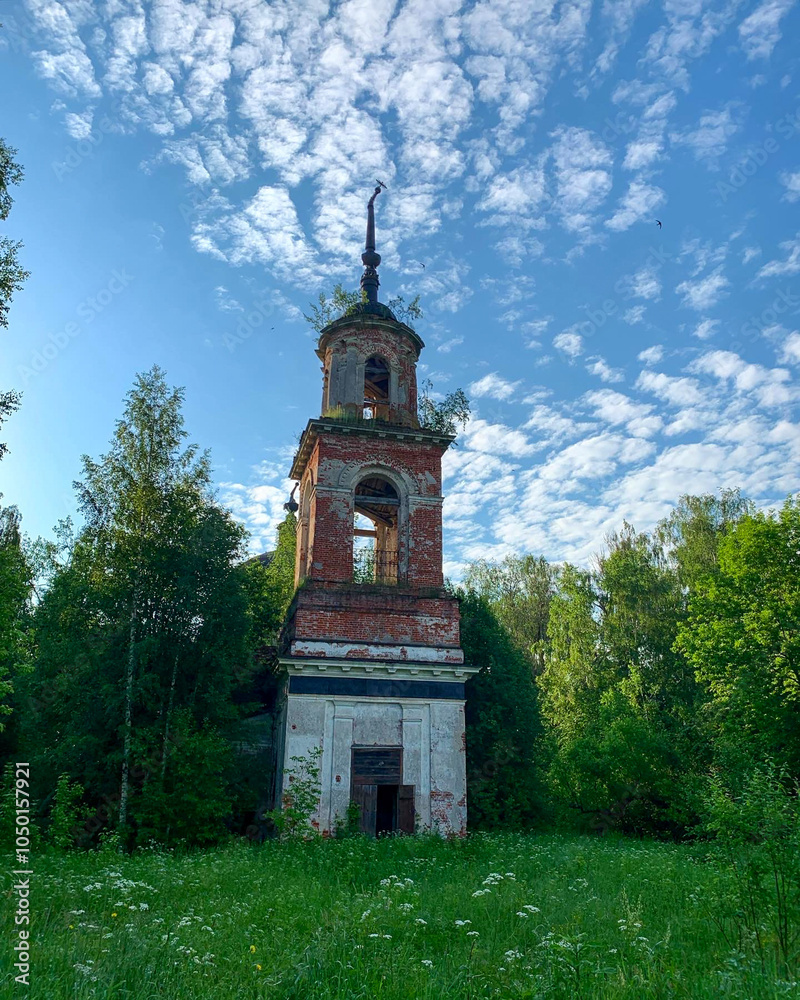 An abandoned, overgrown bell tower stands amidst lush greenery under a blue sky, symbolizing decay and nature's reclaiming power An abandoned, overgrown bell tower stands amidst lush greenery under a blue sky, symbolizing decay and nature's reclaiming power