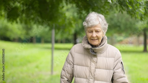 Retired old woman looking at camera relaxed walking in park. Old age senescence concept.MOV