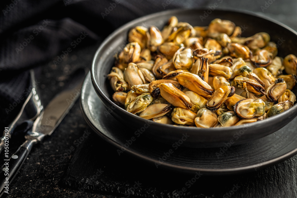 Shelled mussels meat on plate on black table. Shelled mussels meat on plate on black table.
