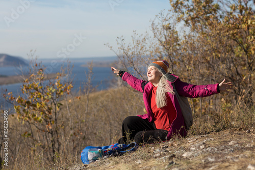 senior woman  with gray hair  sits on the mountain and looks into the distance and walks in autumn outdoor. copy space. mental health. Slow life.  copy space