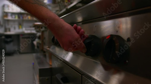 Professional chef turns on the hop and oven in a professional kitchen in slow motion