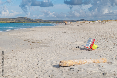 Fototapeta Naklejka Na Ścianę i Meble -  Two empty chairs, one white and one red, on the wide sandy beach of Is Arenas Biancas, Sardinia, Italy