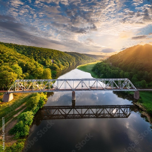 historic steel underspanned suspension railway bridge over bobr river in pilchowice lower silesia poland bird view on bridge shinny sun reflected in the river and beatiful clouds and hills photo