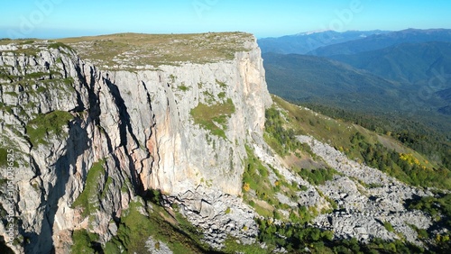 a high cliff with a distant forest in the background. From a bird's-eye view.
