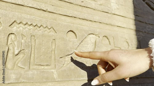 A tourist delicately traces the ancient hieroglyphs inscribed on the walls of the temple of Kom Ombo, dedicated to the crocodile god Sobek.