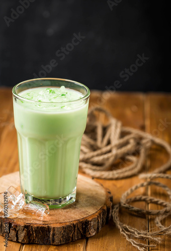 Arabic Green Sharbat or sharbet, matcha latte, topped with ice cubes served in glass isolated on wooden table side view of arabian cold drink photo