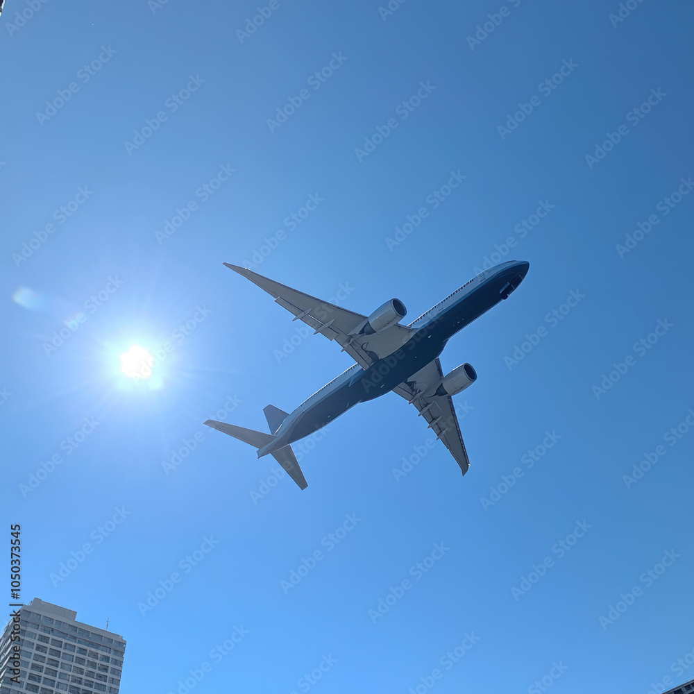 Airplane in Bright Blue Sky with Sunlight Glare Airplane in Bright Blue Sky with Sunlight Glare