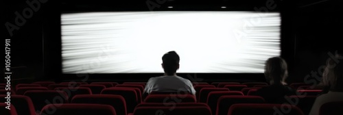 A single figure sits in a darkened theater, facing a blank screen, symbolizing anticipation, the unknown, and the potential for great stories to unfold. photo