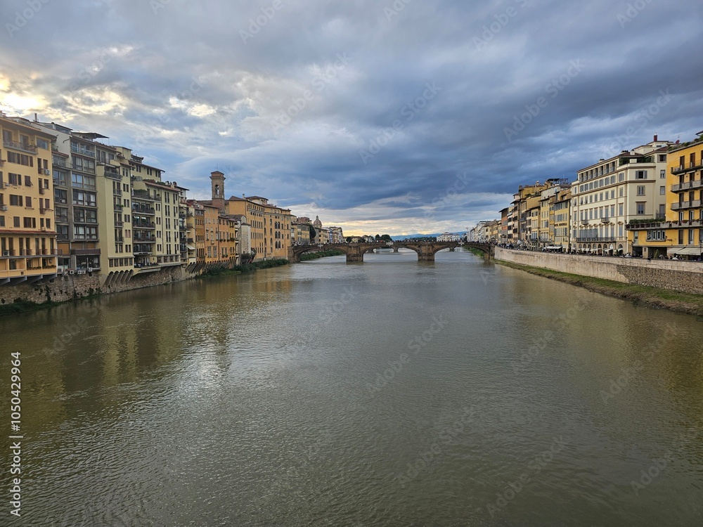 Fototapeta premium Florence, Italy - October 5, 2024: Discovering the city of Florence in autumn days. Frome the Duomo to Ponte Vecchio, old architecture covering the city. Beautiful sky reflected over Arno river.