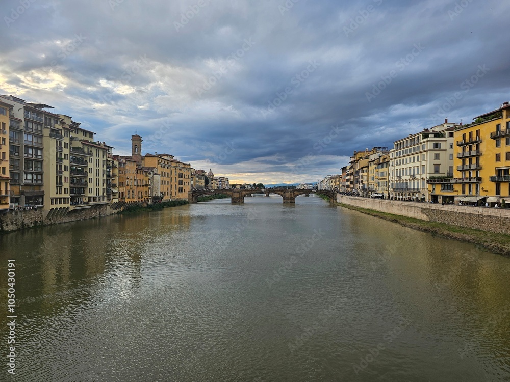 Naklejka premium Florence, Italy - October 5, 2024: Discovering the city of Florence in autumn days. Frome the Duomo to Ponte Vecchio, old architecture covering the city. Beautiful sky reflected over Arno river.