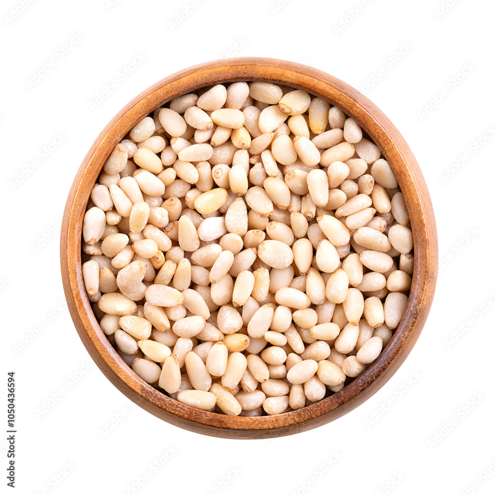 Pine nuts in a wooden bowl, isolated from above. Also known as pinon, pinoli, or pignoli, shelled seeds, fruits of Korean pines, Pinus koraiensis. Used for pesto, added to dishes or baked into bread. Pine nuts in a wooden bowl, isolated from above. Also known as pinon, pinoli, or pignoli, shelled seeds, fruits of Korean pines, Pinus koraiensis. Used for pesto, added to dishes or baked into bread.