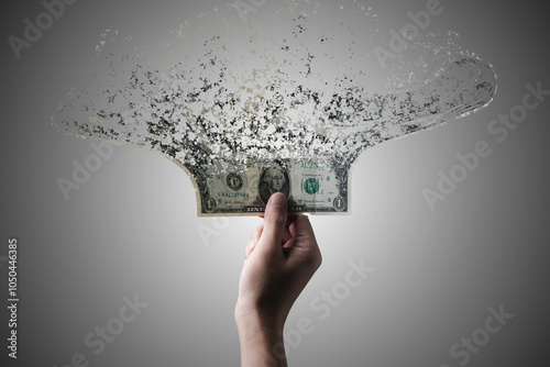 Foto Hand holding US dollar banknote which it is disintegrate into dust particles for money hyper inflation and decreasing power of purchasing concept