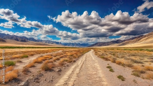 The Dusty Dirt Track Road. Highway in to the mountains, with blue skies and clouds. Ideal Desktop background or Wallpaper.