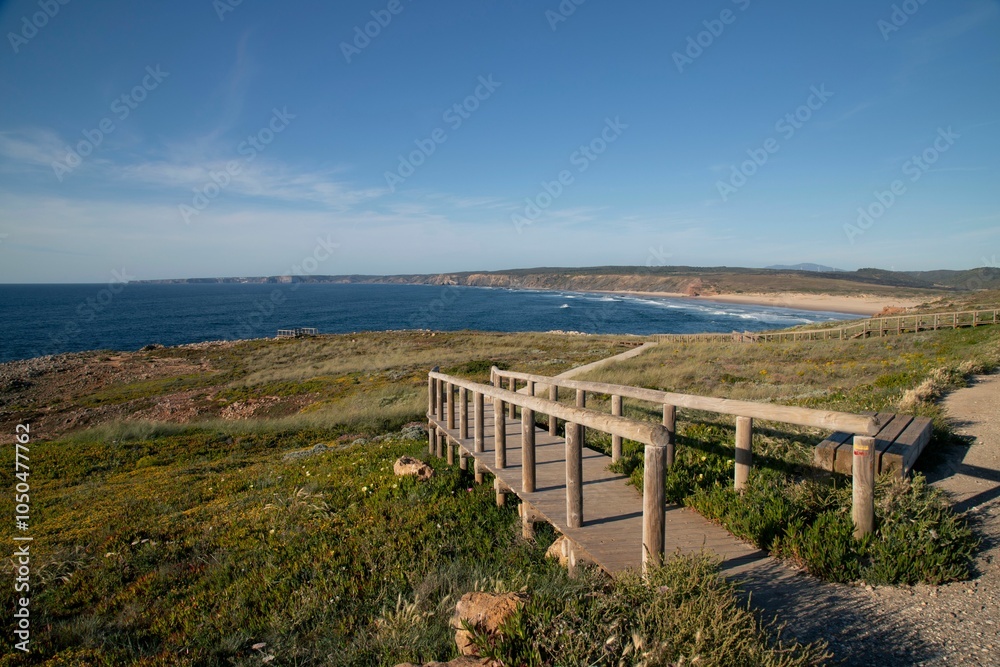 Fototapeta premium Scenic coastal view with a wooden boardwalk leading to a sandy beach in Algarve, Portugal