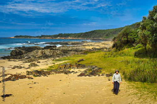 Woman walking along the unspoiled rocky and sandy coast of Cape Conran, along the Cape Conran Nature Trail, Gippsland, Victoria, Australia
