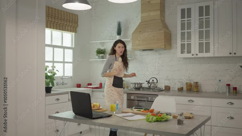 A woman cooks and dances in a modern kitchen with fresh ingredients and plenty of natural light. A woman cooks and dances in a modern kitchen with fresh ingredients and plenty of natural light.