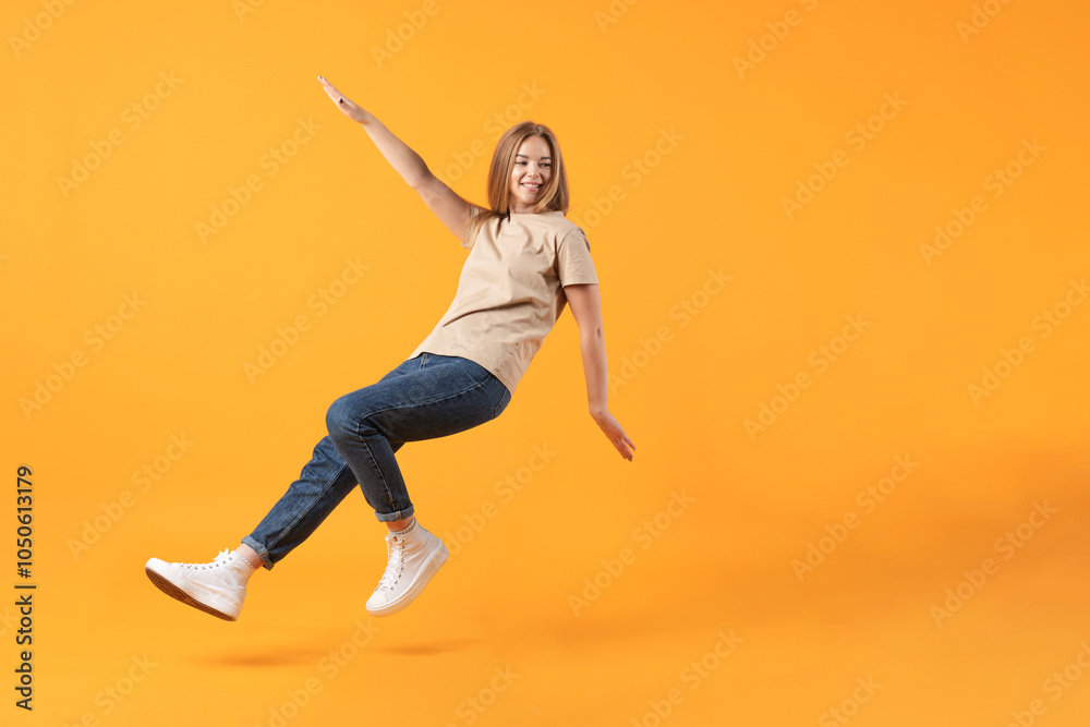 Fototapeta premium Lifestyle, business, commercial concept. A young woman mid-jump with a happy expression on an orange background