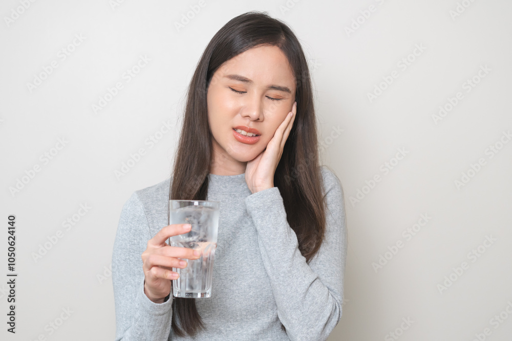 Suffering from toothache, hurt asian young woman touch cheek, face expression ache or feel pain, sensitive molar teeth, hand holding glass of water with ice, inflammation when drink cold, healthcare. Suffering from toothache, hurt asian young woman touch cheek, face expression ache or feel pain, sensitive molar teeth, hand holding glass of water with ice, inflammation when drink cold, healthcare.