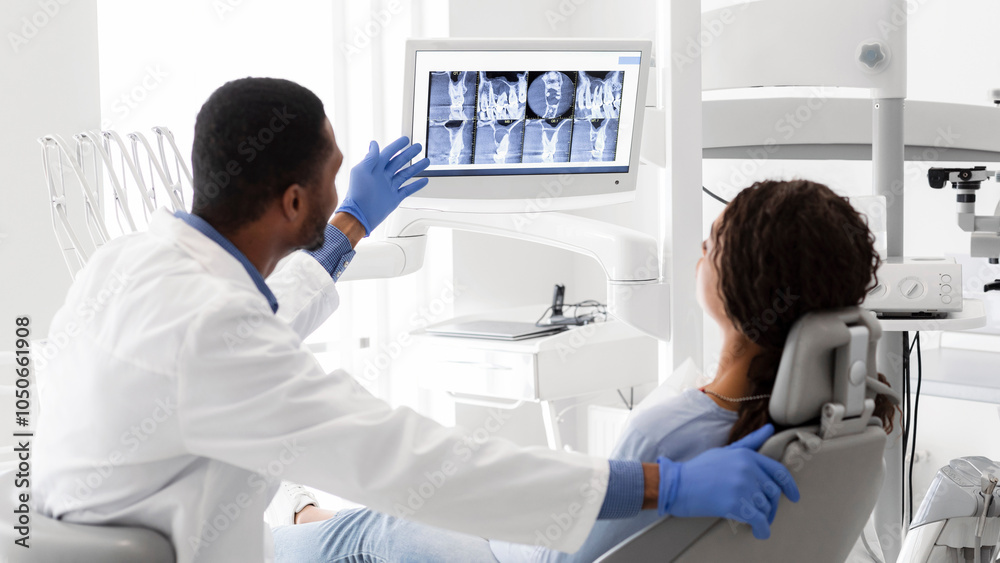 Black Dentist Explaining Xray On Screen To Female Patient At Clinic Black Dentist Explaining Xray On Screen To Female Patient At Clinic