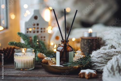 Christmas home aromatherapy. Aroma diffuser with pine extract, organic essential oil, cedar and spruce cone, cinnamon, anise, vanilla scent, candles, wooden table. Cozy atmosphere, winter inspiration photo