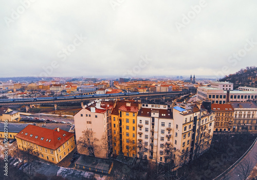 Overcast cityscape view of Prague city, Czechia. Highlighting rows of colorful residential buildings in a cloudy winter day. Railway bridge on background, Vitkov hill on the right photo