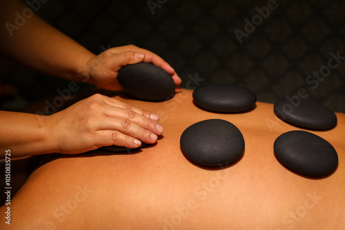 In a massage parlor, a woman gives a man stone therapy using hot stones photo