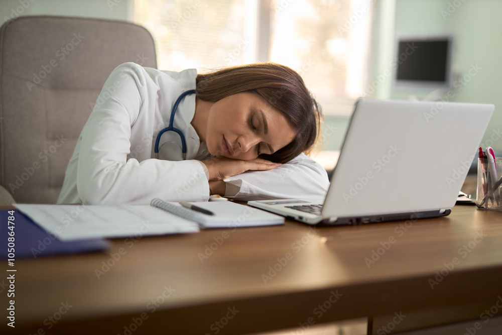 Overworked female doctor taking a nap in her office. Overworked female doctor taking a nap in her office.