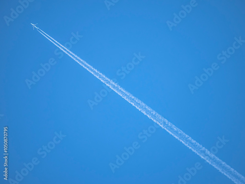 White streaks of planes leave behind like artificial clouds crossing the image diagonally across the photograph on a blue sky background