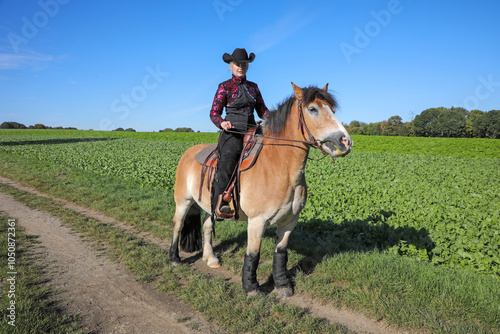 Westernreiten - Reiterin mit Cowboyhut mit Ihrem Pferd photo