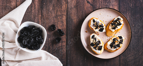 Homemade bruschetta with cream cheese and prunes on a plate top view web banner