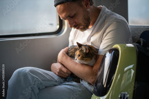 Фотография Man traveling on train with beloved cat sitting calmly on lap