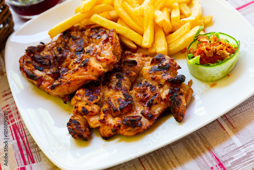 Traditional Balkan dish Pileci Batak, grilled boneless chicken thighs served with french fries and sauce photo