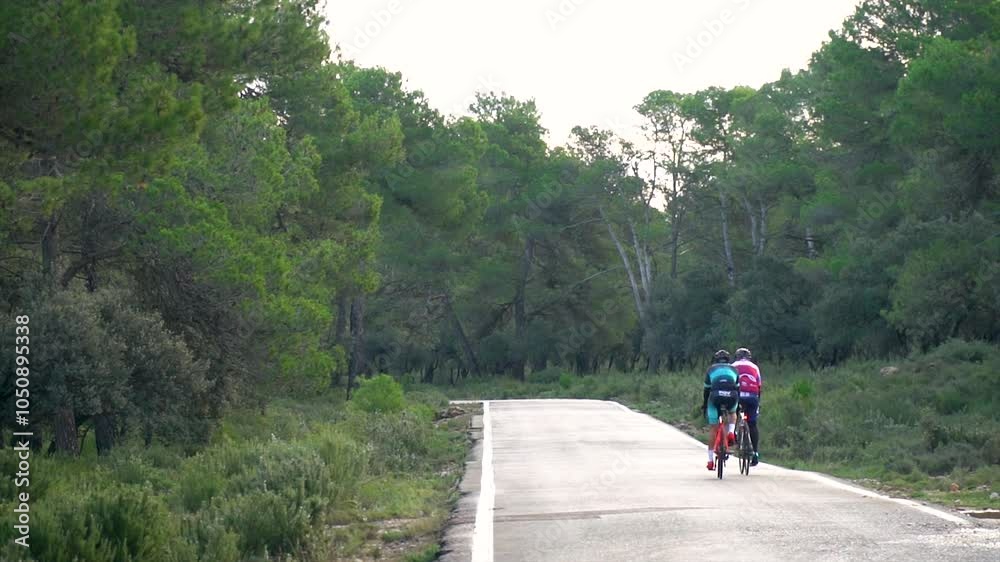 Slow motion, two cyclists racing along a narrow mountain road. Slow motion, two cyclists racing along a narrow mountain road.