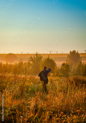 Man in the forest , landscape photographer in work , camera man hiking in the forest , autumn forest ,sunrise . Photographu in forest . Man with hat , brutal boy walking in forest  photo