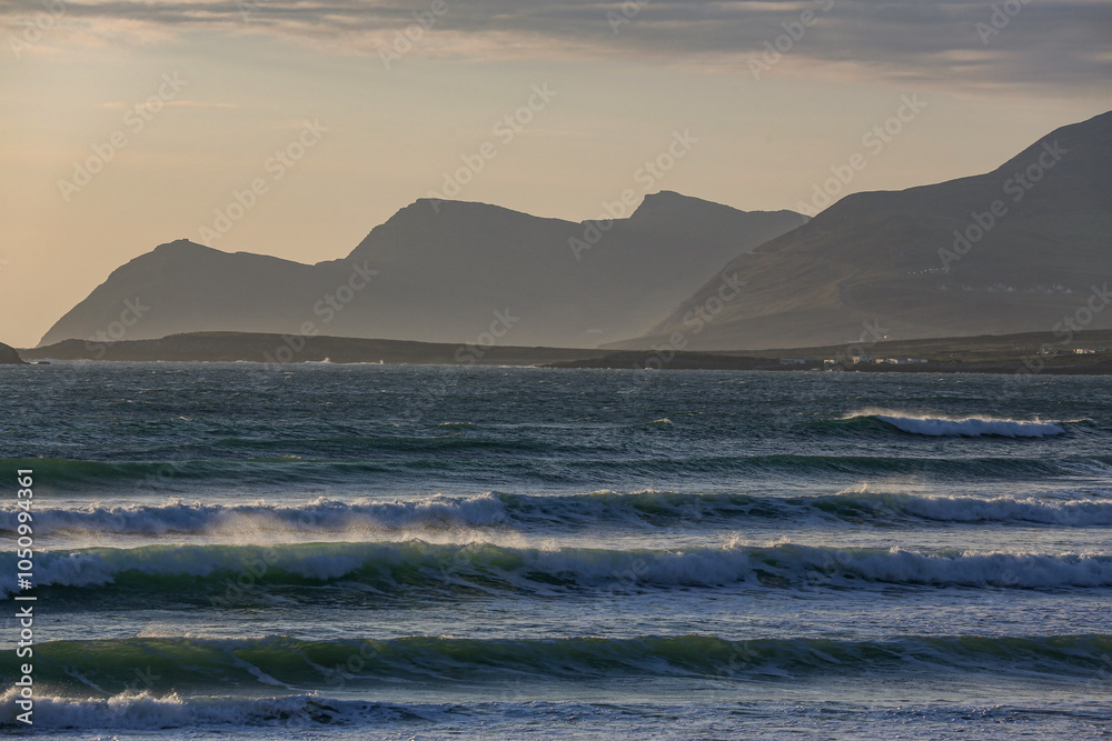 Obraz premium Mystische Stimmung am Strand von Keel Beach auf der Halbinsel Achill Island in Irland. Wellen und Berge, etwas nebel und die Abendämmerung.