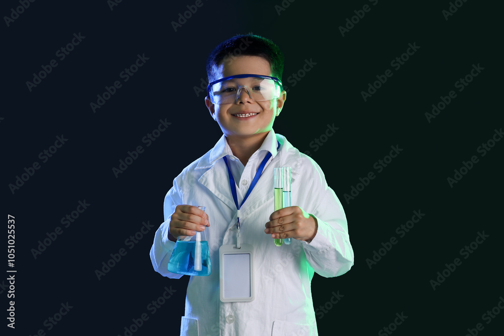 Cute little boy with chemical flasks on black background Cute little boy with chemical flasks on black background