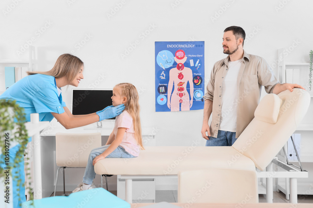 Obraz premium Female endocrinologist examining thyroid gland of little girl and her father in clinic