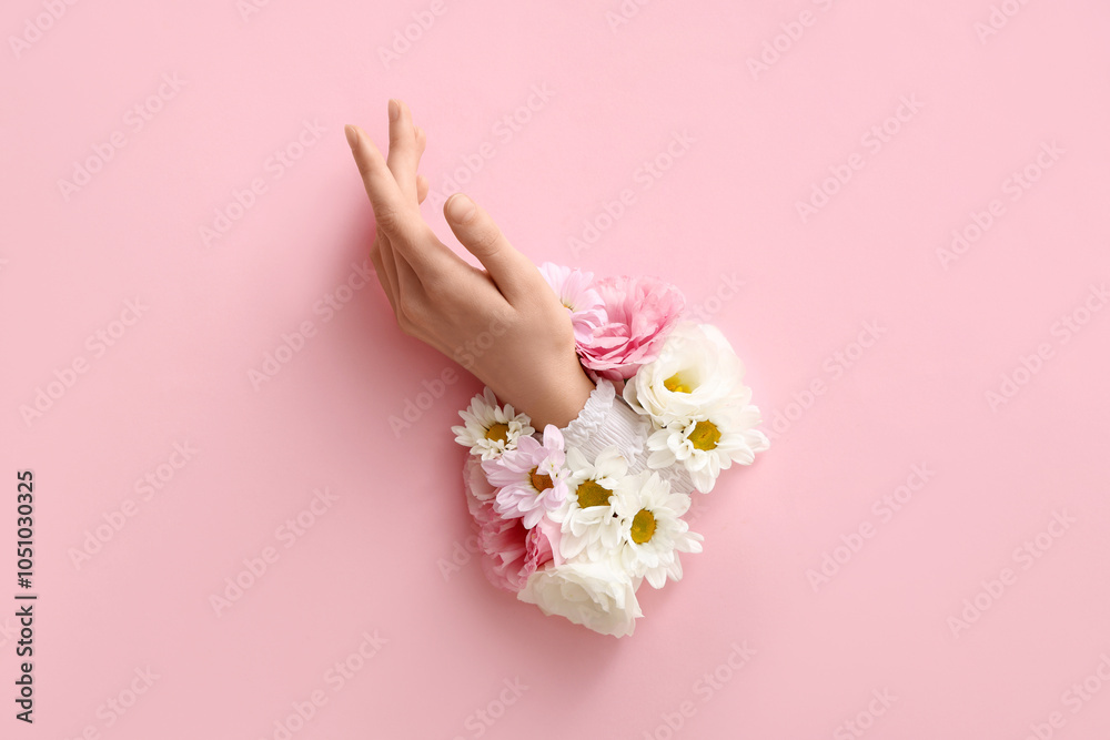 Female hand with different fresh flowers visible through hole in pink paper Female hand with different fresh flowers visible through hole in pink paper