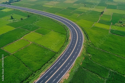 Aerial view of a curved road surrounded by lush green fields.